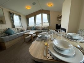 A living room with a sofa and dining table at Blue Dolphin Holiday Home in Gristhorpe