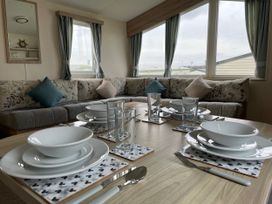 A dining area with plates and glasses set on a table at Blue Dolphin Holiday Home in Gristhorpe