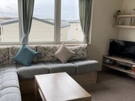 A living room with a sofa and television at Blue Dolphin Holiday Home in Gristhorpe