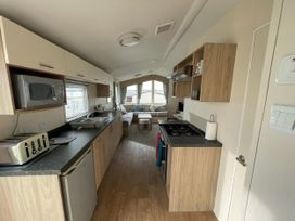 A kitchen with appliances and a seating area at Blue Dolphin Holiday Home in Gristhorpe