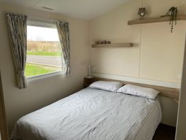 A bedroom with a bed and a window at Blue Dolphin Holiday Home in Gristhorpe