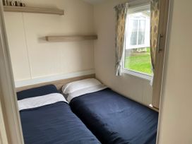 A bedroom with two beds and a window at Blue Dolphin Holiday Home in Gristhorpe