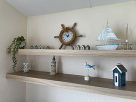 A shelf with decorative items including a clock and a sailboat at Blue Dolphin Holiday Home in Gristhorpe