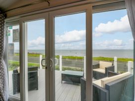A living room with sliding glass doors and a view of the sea at Caravan in Girvan