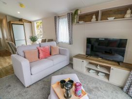A living room with a sofa and television at Caravan in Girvan