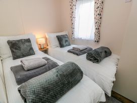A bedroom with two beds and a lamp at Caravan in Girvan