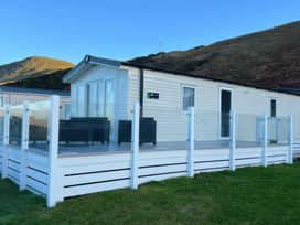 A mobile home with a deck and outdoor furniture at Frontline Sea View : P1 Whilk Meadow in Girvan