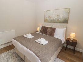 A bedroom with a bed, blanket, towels, lamp and radiator at Flat 1 in Tenby