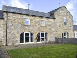A garden with a stone wall house and outdoor furniture at The Hayloft in Hexham