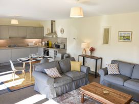 A living room with a sofa, coffee table, and kitchen area at The Hayloft in Hexham