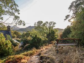A garden with a bench and trees overlooking mountains at Y Cwtch in Dolgellau