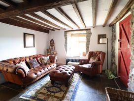A living room with a leather sofa and an ottoman at Waen Fechan in Dolgellau