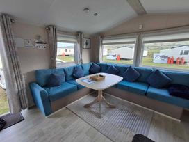 A living room with a blue sofa and table at Lyons Sunnysands - Snowdon Summit 050 Talybont