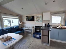 A living room with a blue sofa and television at Lyons Sunnysands - Snowdon Summit 050 in Talybont