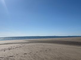 A beach with sand and ocean under a clear sky at Lyons Sunnysands - Snowdon Summit 050 in Talybont