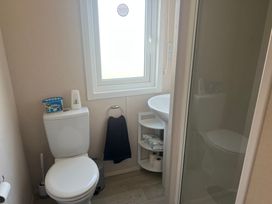 A bathroom with a toilet, sink, and shower at Lyons Sunnysands - Snowdon Summit 050 Talybont