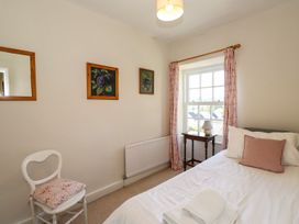 A bedroom with a bed and a chair at Jessicas Cottage in Windermere