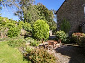 A garden with a table and chairs surrounded by greenery at Jessicas Cottage Windermere