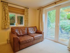 A living room with a sofa and a door leading to a garden at Coombe Cottage Apartment in Axmouth