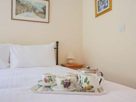 A bedroom with a tray of tea on the bed at Coombe Cottage Apartment in Axmouth