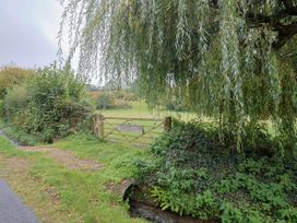 A pathway leading to a gate amidst green bushes at Coombe Cottage Apartment Axmouth