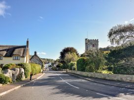 A street view with thatched house and stone building at Coombe Cottage Apartment Axmouth