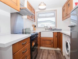 A kitchen with a sink, stove, and washing machine at 122 Norton Park in Dartmouth