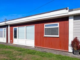 An exterior view of a red wooden wall with windows and doors at 122 Norton Park in Dartmouth