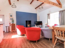 A living room with red and grey sofas and a television at Hen Blas in Pwllheli