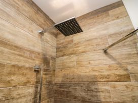 A shower with a square shower head and wooden panel wall at 10 Rayrigg Rise Bowness-On-Windermere