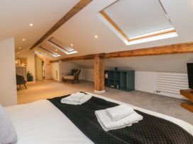 A loft with a bed, skylights, and a shelving unit at 10 Rayrigg Rise Bowness-On-Windermere