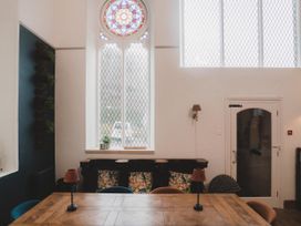 A dining room with a stained glass window and table at Chapel of Arts in Criccieth
