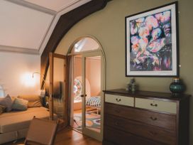 A bedroom with a sofa, dresser, and a painting at Chapel of Arts in Criccieth