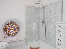 A bathroom with a shower and stained glass window at Chapel of Arts in Criccieth