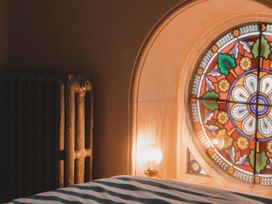 A bedroom with a stained glass window and a radiator at Chapel of Arts in Criccieth