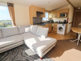 A living room with a kitchen area and sofa at No.73 Sennen Cove