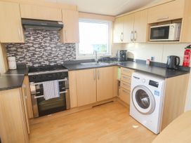 A kitchen with a stove, sink, and washing machine at No.73 Sennen Cove