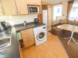 A kitchen with a washing machine and dining area at No.73 Sennen Cove