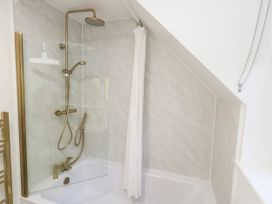 A bathtub with a shower setup at Osmington Cottage Annex