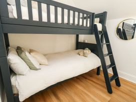 A bedroom with a bunk bed and a ladder at Osmington Cottage Annex