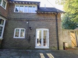 An outdoor view of the back of a brick house with a patio area at Osmington Cottage Annex