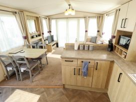 A living room with kitchen area and dining table at Coastfields Holiday Village in Ingoldmells