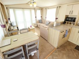 A living room and kitchen area with a sofa and dining table at Coastfields Holiday Village in Ingoldmells