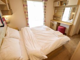 A bedroom with queen bed and a dressing table at Coastfields Holiday Village in Ingoldmells