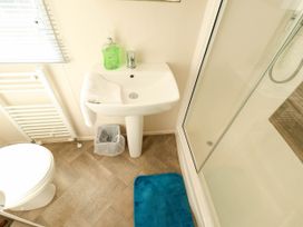 A bathroom with a sink, toilet, shower, and radiator at Coastfields Holiday Village in Ingoldmells
