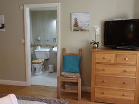 A bedroom with a chair and television and a bathroom doorway at High Beck in Kendal