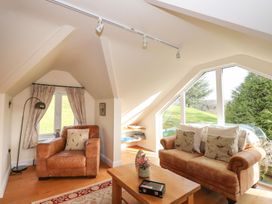 A snug with a sofa and chair beside a window at High Beck Cottage in Kendal