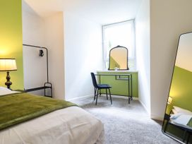 A bedroom with a bed, desk, chair, mirror, and lamp at Flat 1 Greenfields in Barmouth