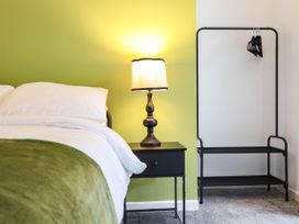 A bedroom with a bed, nightstand, lamp, and clothing rack at Flat 1 Greenfields in Barmouth