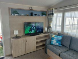 A living room with a television and sofa at St Osyth Beach in Clacton-on-Sea